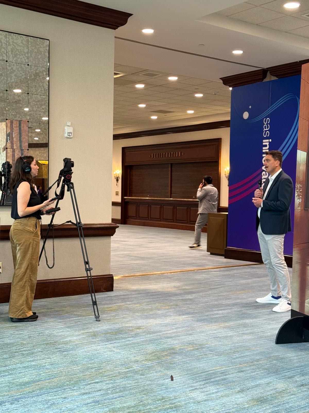 Piotr Pach speaking with a microphone while being filmed at SAS Innovate 2026